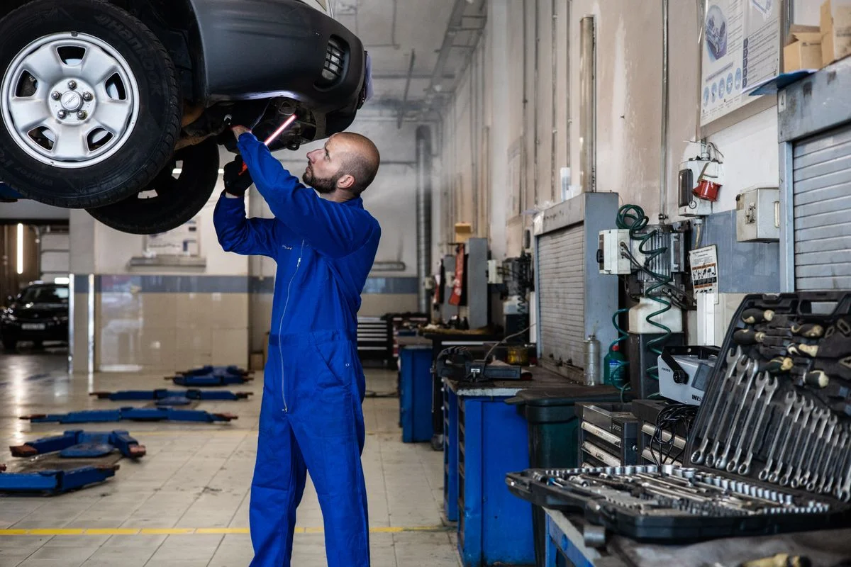 Mechanic examining the underside of a raised car in a workshop