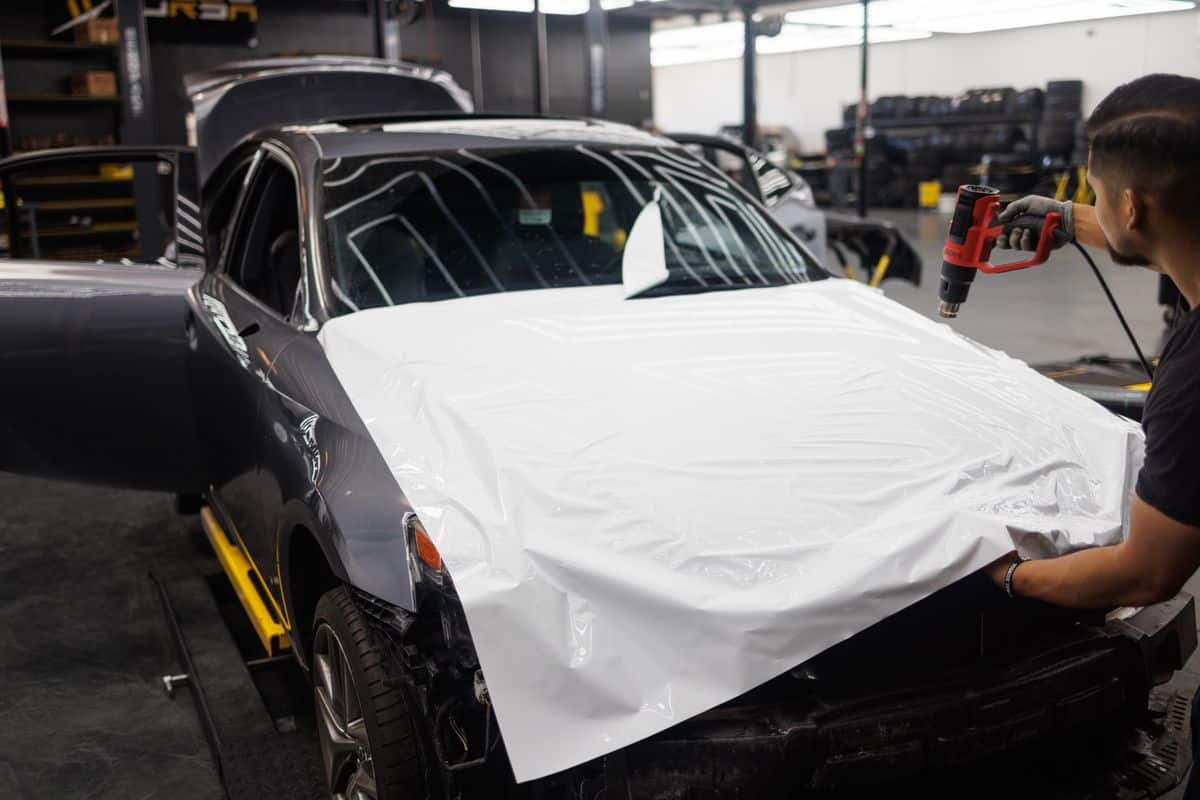 Installer shaping vinyl film over a hood with controlled heat