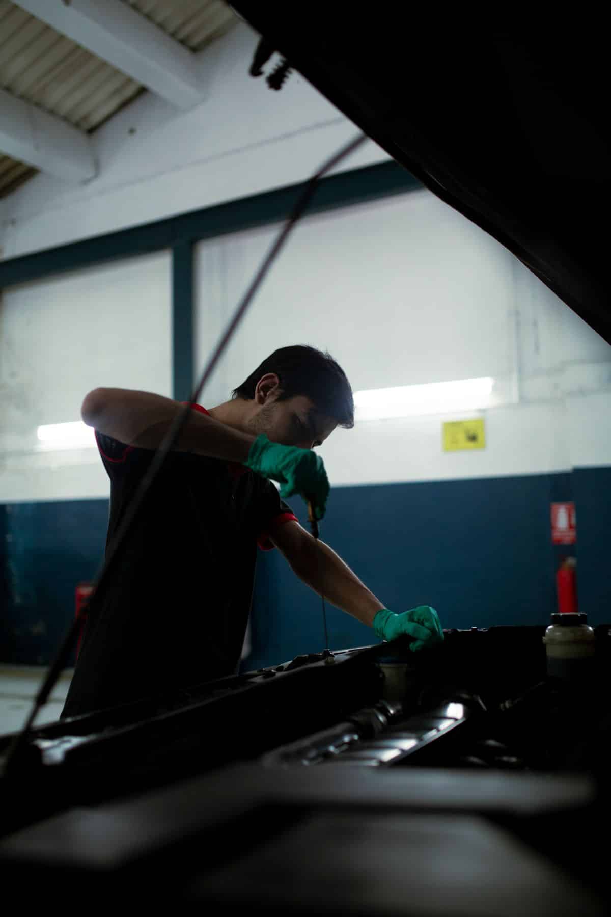 Mechanic checking a car’s engine oil with a dipstick