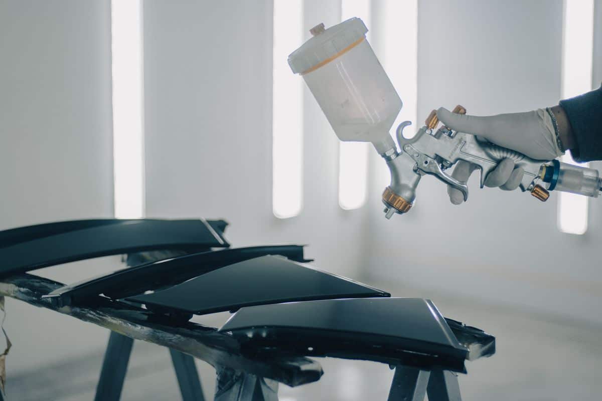 Spray gun applying a finish to automotive trim components