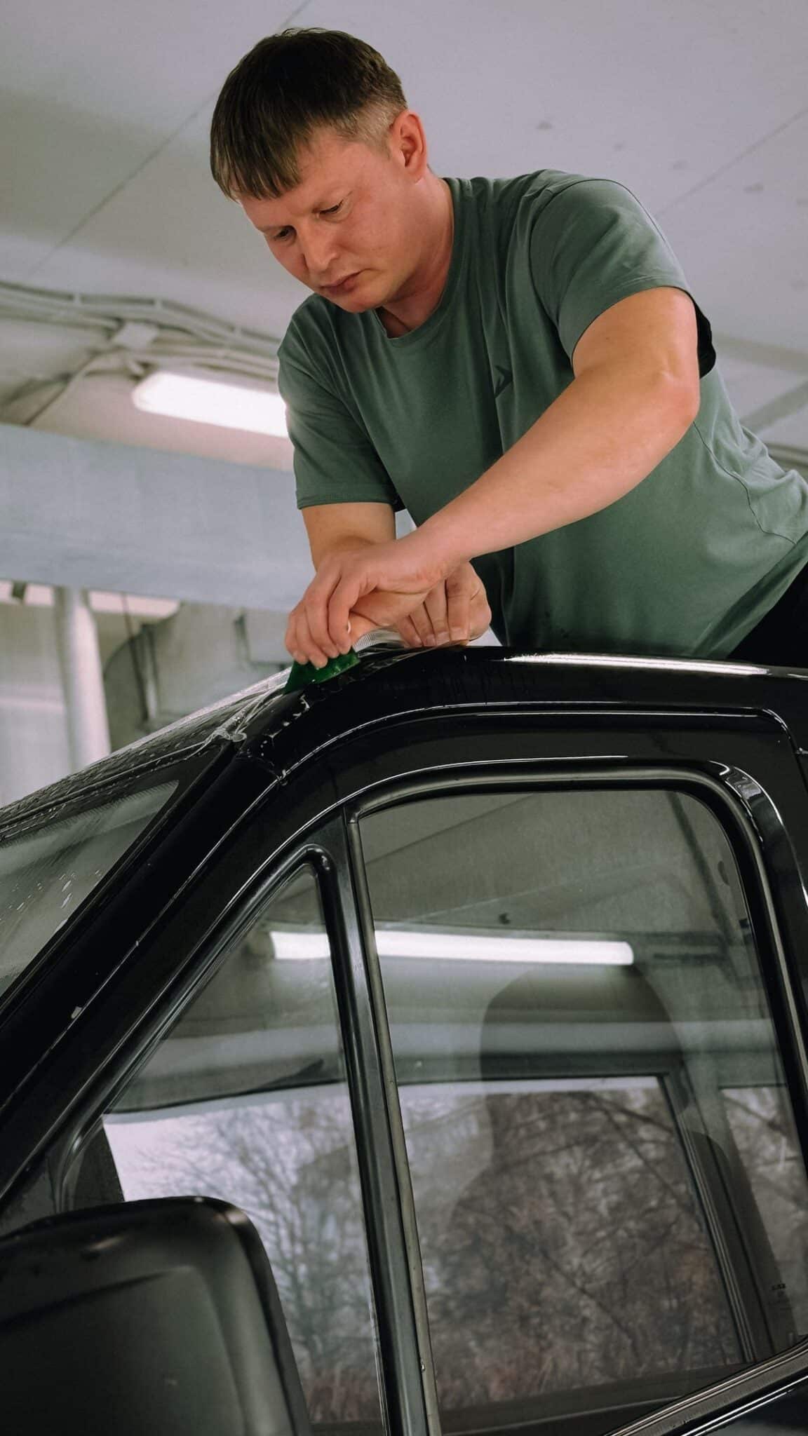 Installer working with automotive window film on a car