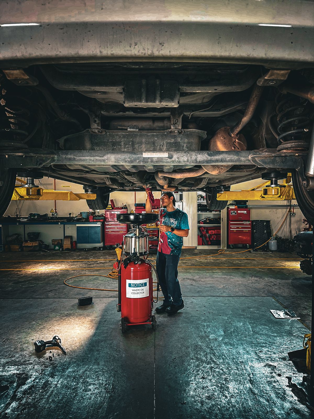 Mechanic working beneath a vehicle raised on a workshop lift