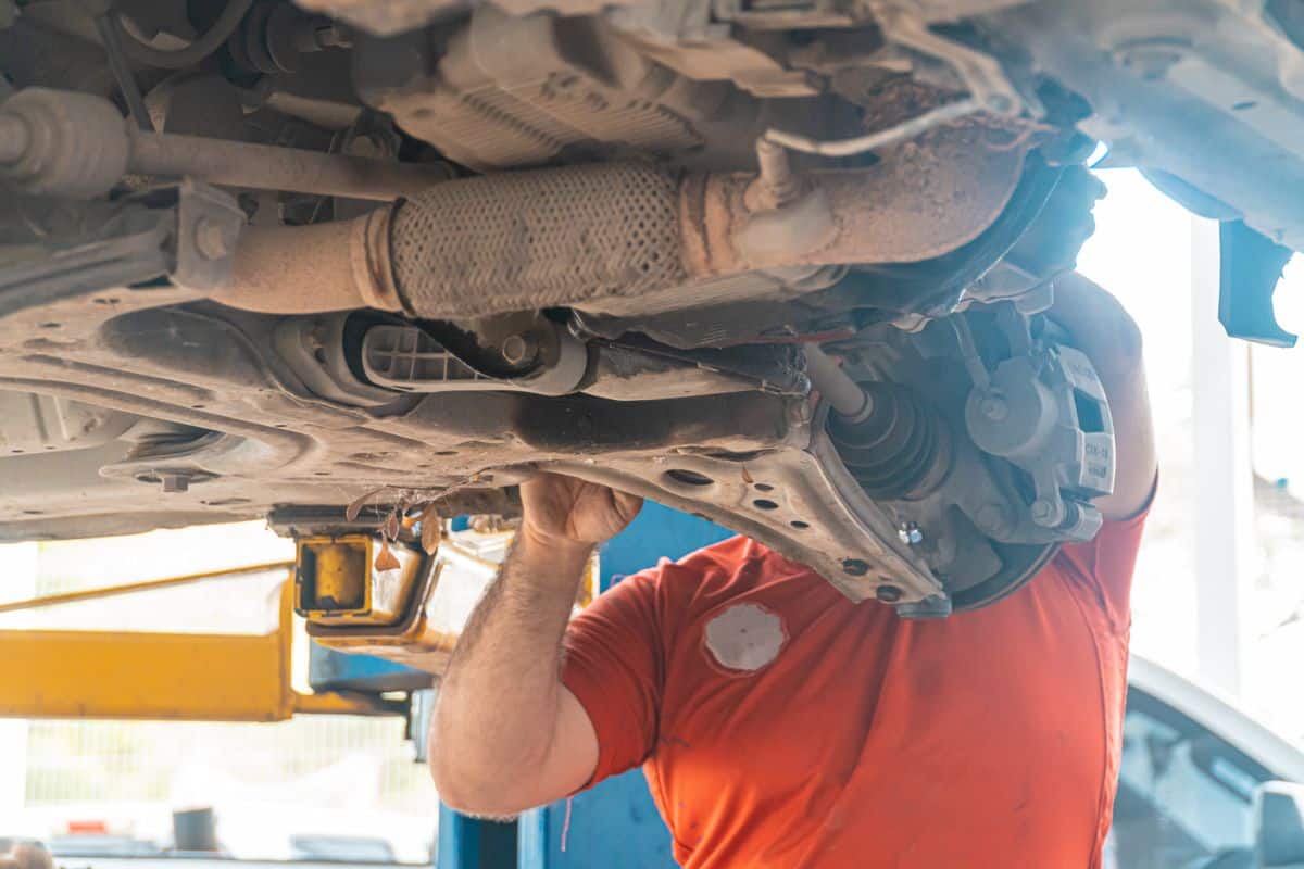 Mechanic inspecting suspension components beneath a raised car