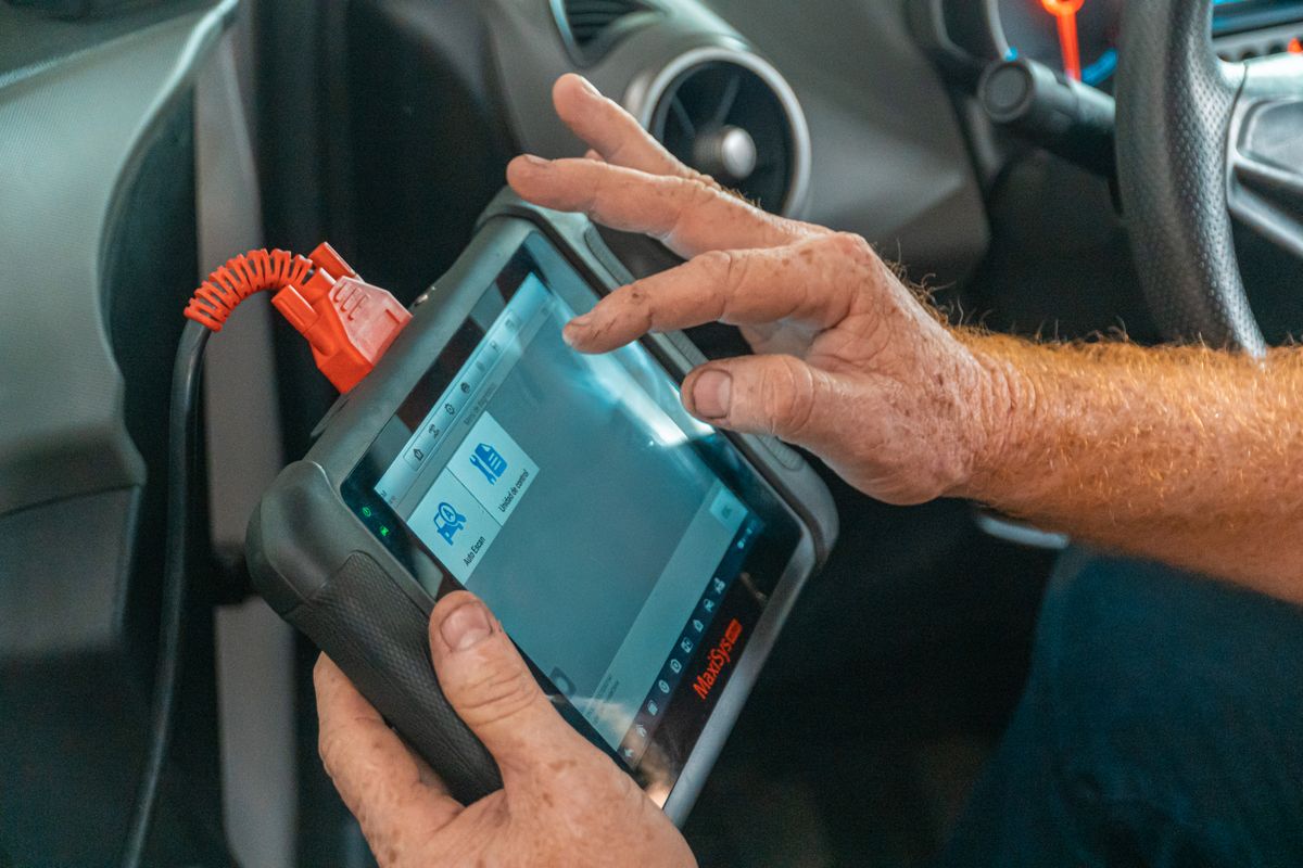 Technician using a diagnostic scanner inside a vehicle