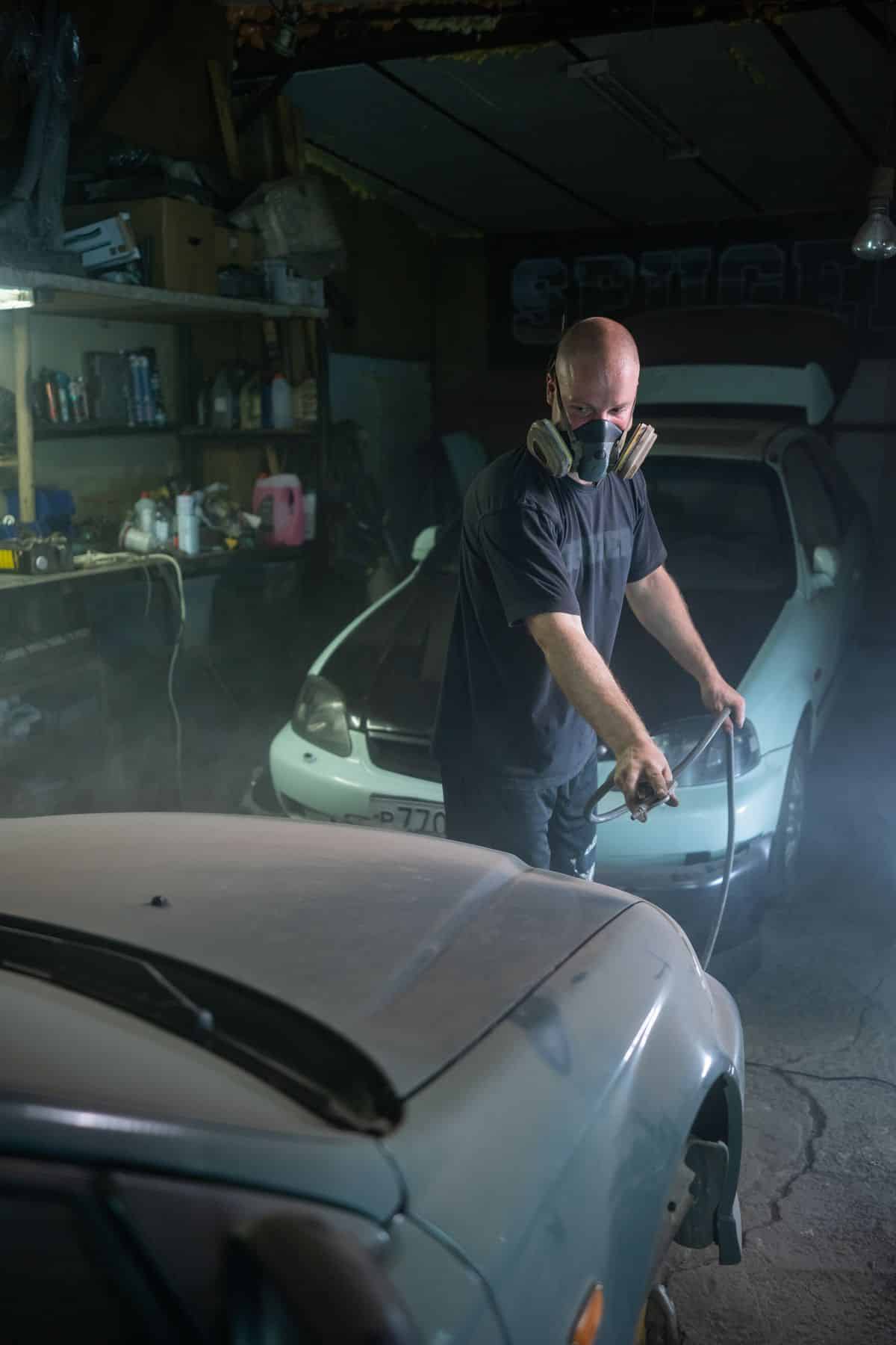 Bodywork technician working on a car panel in a repair workshop