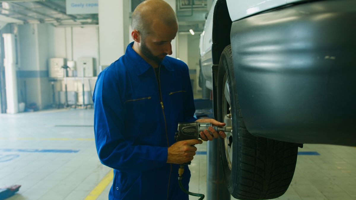 Mechanic removing a wheel to access components for inspection