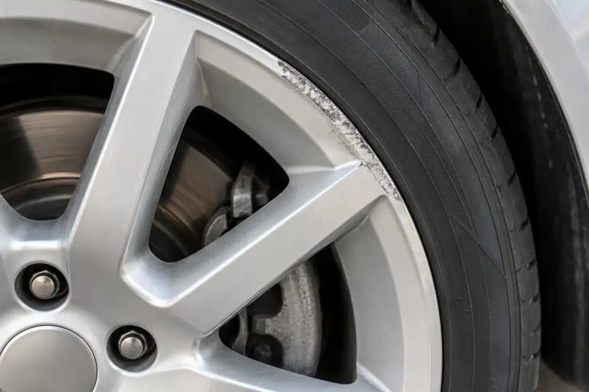 Curb scuffs along the outer lip of a silver alloy wheel