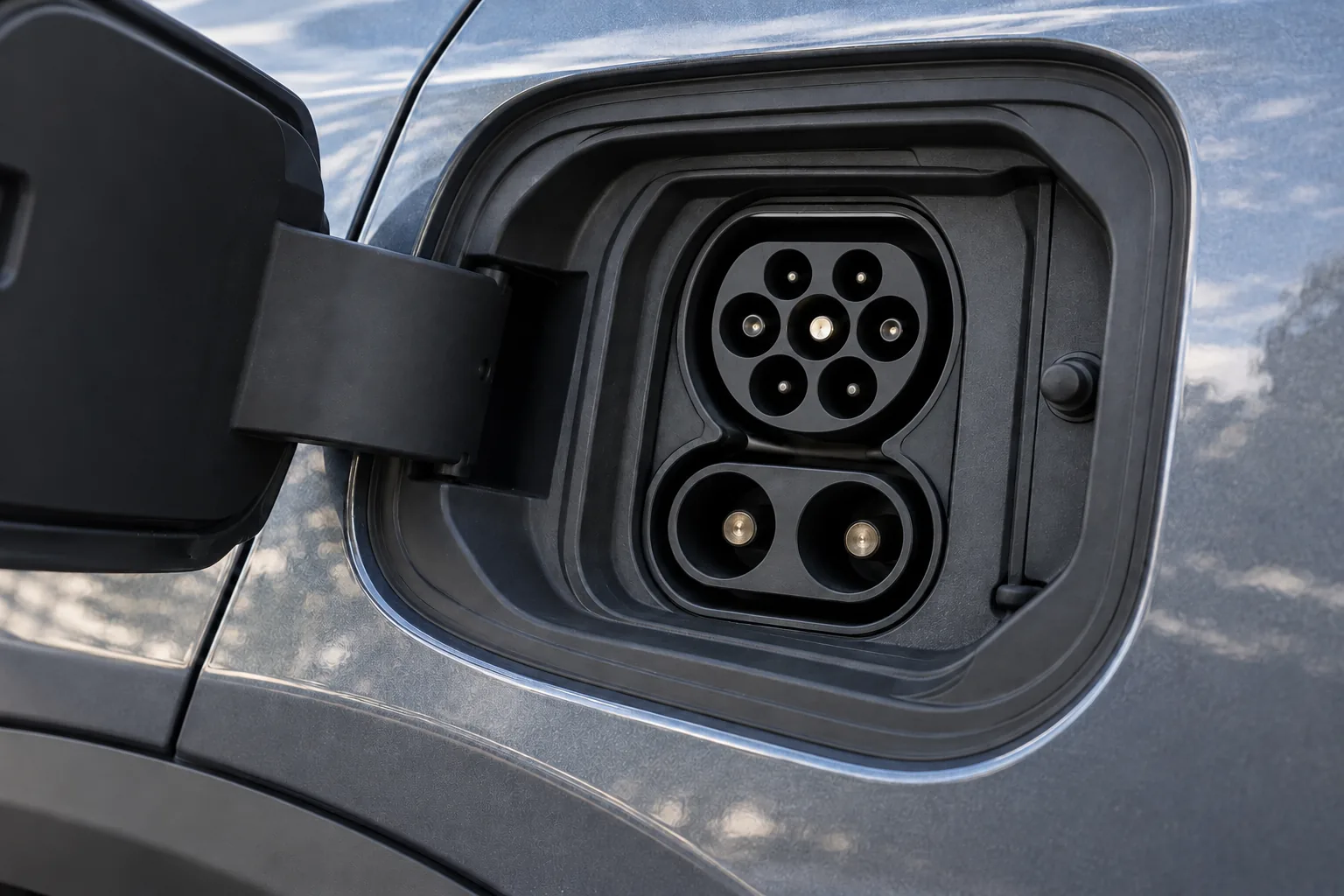 Open electric car charging inlet with an upper AC socket and two lower DC contacts