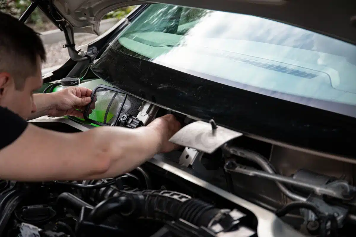 Technician working on components at the rear of an engine bay