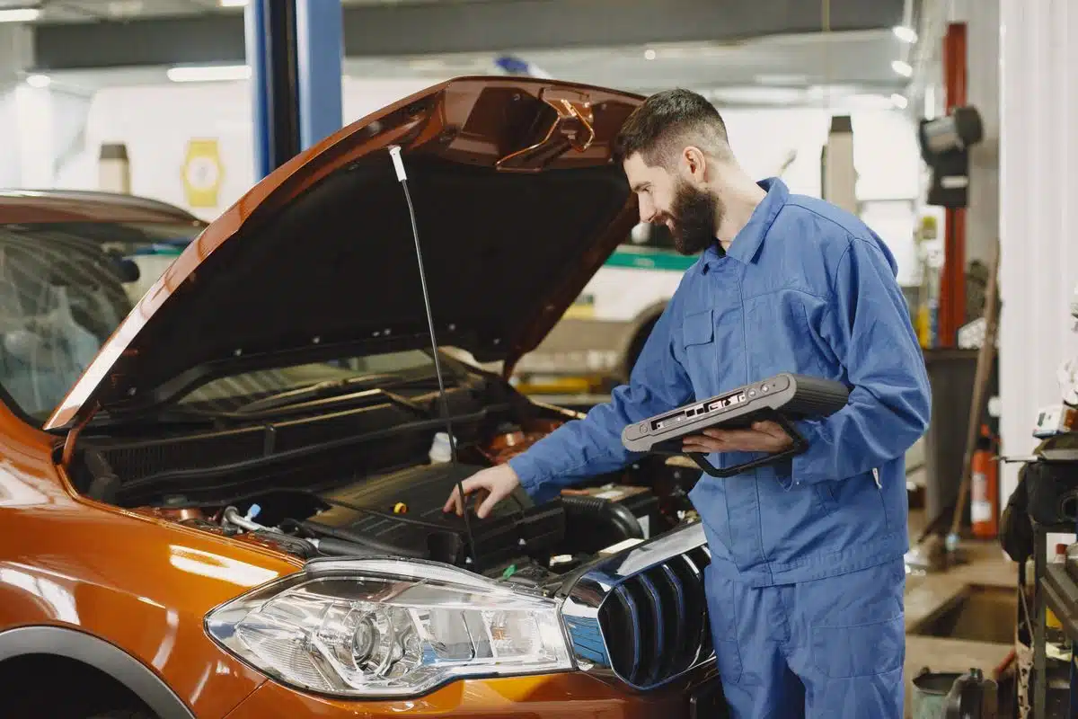 Technician using a diagnostic tablet beside an engine