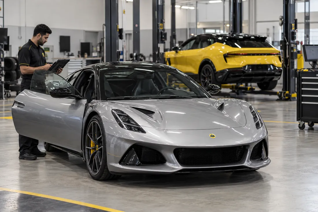 Technician reviewing a Lotus sports car in a garage with an electric Lotus in another bay