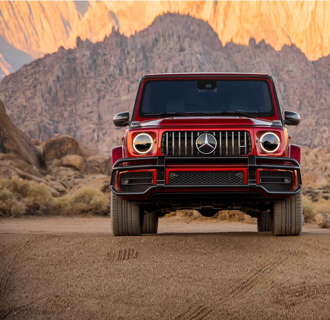 Red Mercedes-AMG G63 viewed from the front against a desert landscape