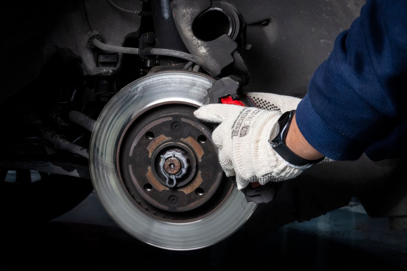 Technician inspecting a brake disc and caliper with the wheel removed