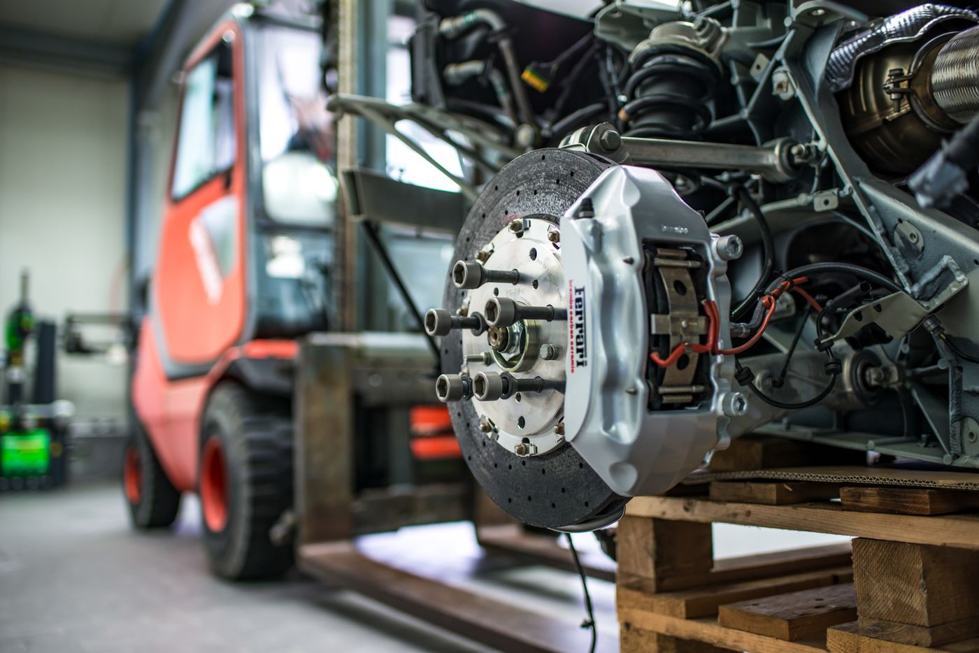 Ferrari brake caliper and disc with suspension components exposed in a workshop