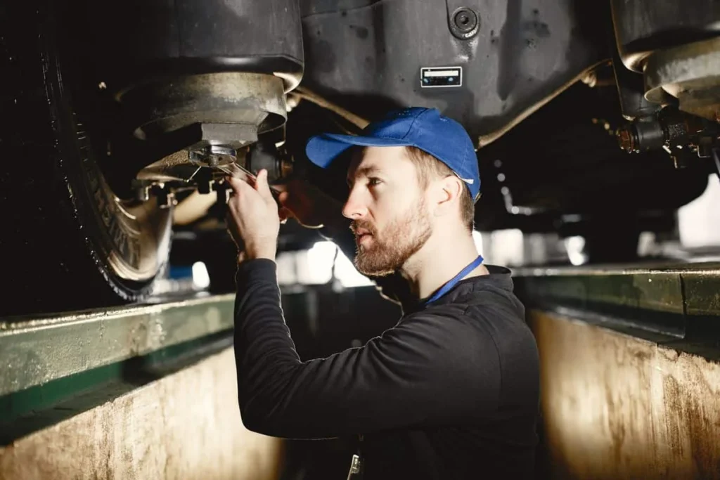 Technician inspecting the underside of a vehicle in a workshop