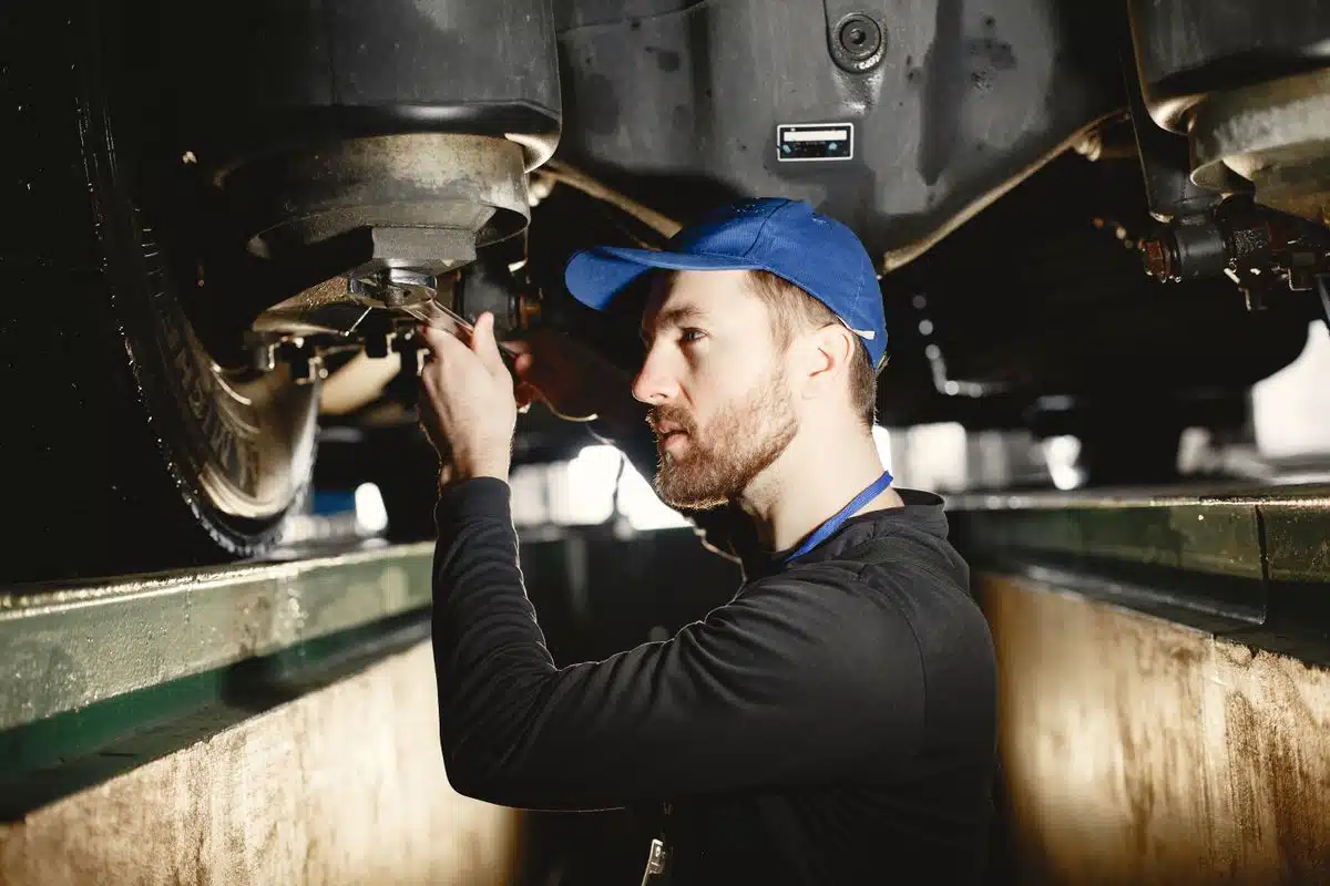 Technician inspecting vehicle components from an inspection pit