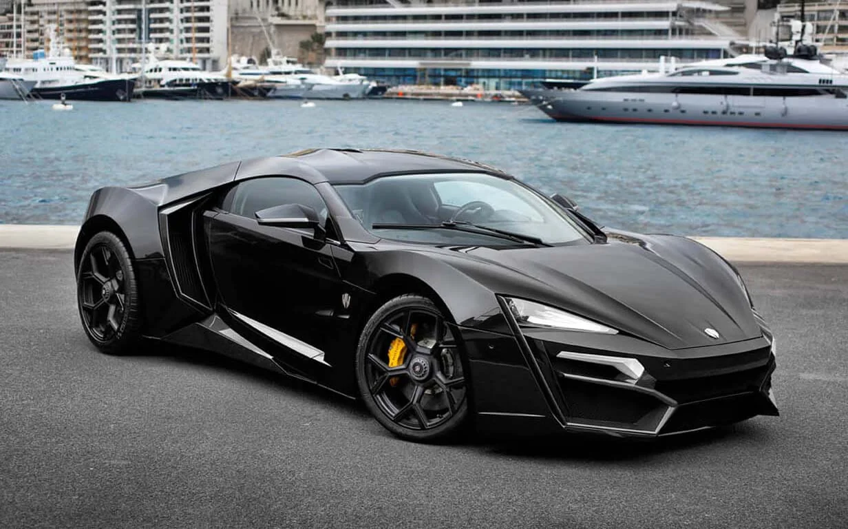 Black Lykan HyperSport parked beside waterfront buildings